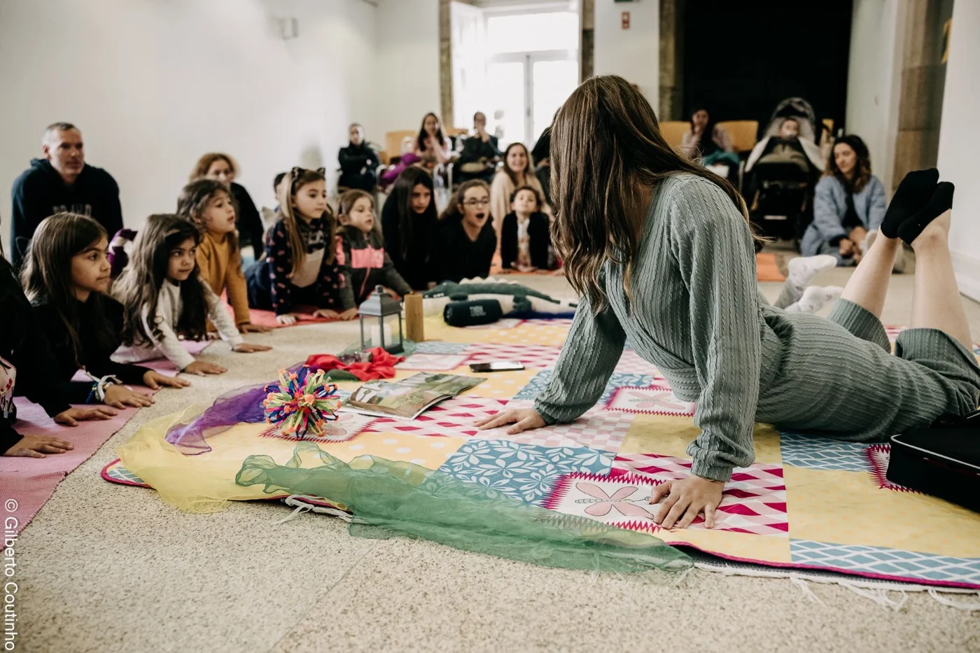 Carla demonstra uma postura de yoga numa sessão com crianças e famílias