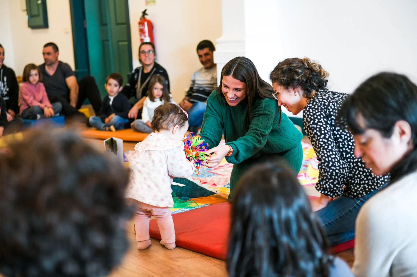 Carla Moreira sorri e explora uma esfera colorida com uma criança numa sessão ArtYoga em família